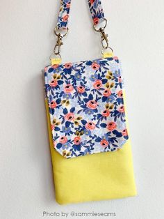 a purse hanging on the wall with a flowered fabric and yellow strap around it