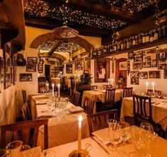 a dining room with tables and chairs covered in white tablecloths, lit by candles