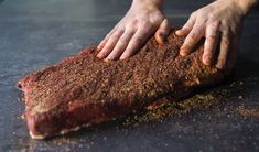 a person with their hands on top of a piece of meat that has been seasoned