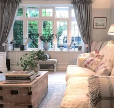 a living room filled with furniture next to a window covered in curtains and drapes