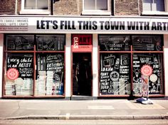 a storefront with chalk writing on the front and windows that say let's fill this town with art