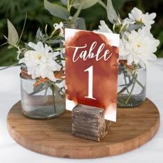 there is a table number with flowers in the vases on the table and a sign that says table 1