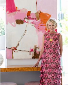 a woman standing in front of a large painting with pink and orange designs on it