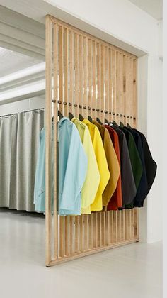 an open closet with clothes hanging on the wall and several different colored shirts in it