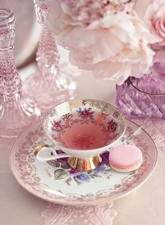 a tea cup and saucer with pink flowers in the background