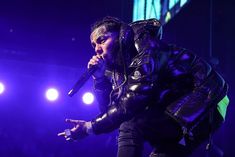 a man in black leather jacket on stage with microphone