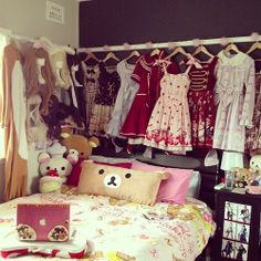 a bedroom with teddy bears and clothes hanging on the rack above it's bed