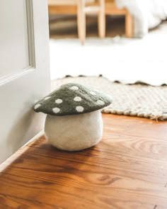 a mushroom sitting on top of a wooden floor next to a white door frame and rug