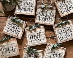 christmas ornaments made out of old newspaper are hanging on a wooden table with greenery