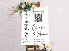 a wedding sign with flowers on it next to a brick wall and wooden easel