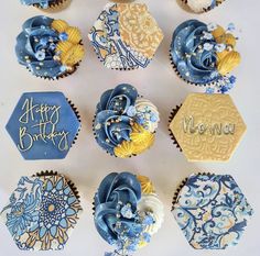 cupcakes decorated with blue and yellow icing are arranged on a white surface