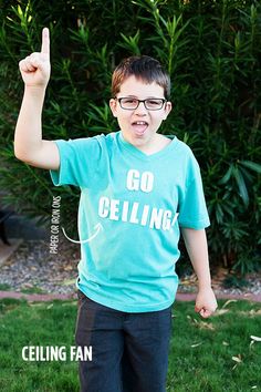 a young boy wearing glasses and pointing to the side while standing in front of some bushes