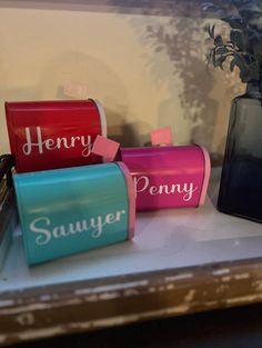 three different colored boxes sitting on top of a table next to a vase with flowers in it