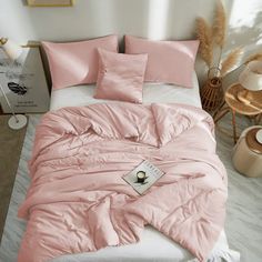 a bed with pink sheets and pillows on it