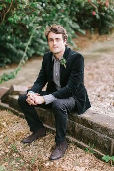 a man in a suit sitting on a stone wall