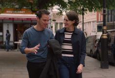 a man and woman walking down the street talking