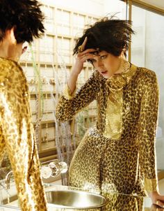 a woman is looking in the mirror with her hair up and wearing a leopard print dress