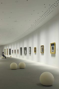 an art gallery filled with lots of white balls and paintings on the wall next to each other