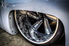 the front wheel of a silver car with chrome rims and decorative designs on it