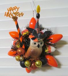 an orange and black wreath with an owl wearing a witch's hat