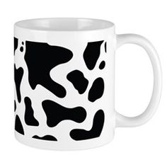 a white coffee mug with black and white cow print on it's side, in front of a white background