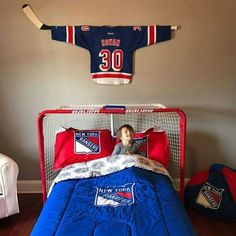 a young boy is laying in his bed with hockey jersey on the wall above him