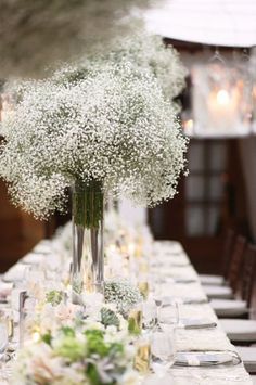 the table is set with white flowers and place settings for an elegant dinnereon party