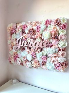 a pink and white flower wall with the word love spelled on it