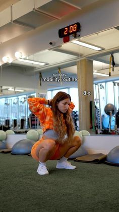 a woman squatting down in the middle of a gym