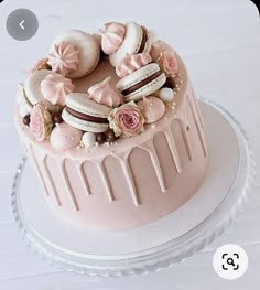 a pink cake with macaroons and flowers on top