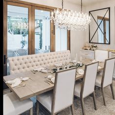 a dining room table with white chairs and a chandelier