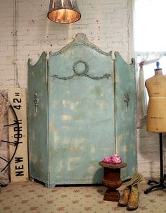 an old blue cabinet next to a pair of shoes and a lamp hanging from the ceiling