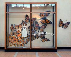 there is a display case with many butterflies in the glass and on the wall are two mannequins