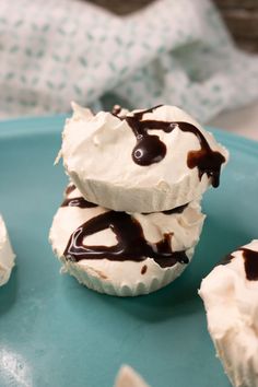 three cupcakes with white frosting and chocolate drizzled on top