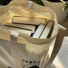 there is a bag with books in it on the table next to a potted plant