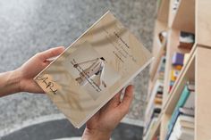 a person holding an open book in front of a bookshelf filled with books