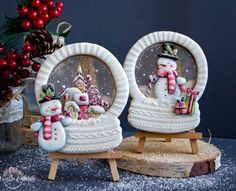 two snow globes sitting next to each other on a wooden stand with christmas decorations