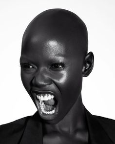 a woman with her mouth open wearing black makeup and a balding head is posing for the camera