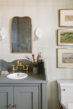 a bathroom with a sink, mirror and pictures on the wall above it's vanity