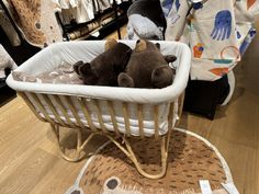 three stuffed animals in a white basket on the floor next to clothing racks and baby clothes