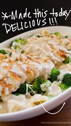 a white bowl filled with pasta and broccoli covered in gravy on top of a wooden table