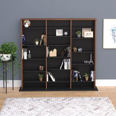 a bookcase with many books and plants on it in the corner of a room