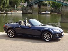 a black sports car parked in front of a body of water