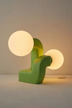 a green chair sitting next to a lamp on top of a white floor covered in light