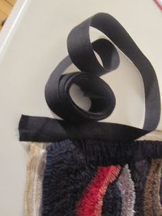 a pair of scissors sitting on top of a piece of cloth next to a roll of black ribbon