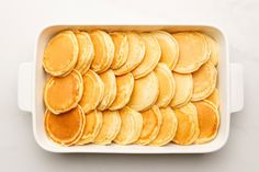 a white dish filled with pancakes on top of a table