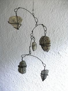 a metal wind chime with shells hanging from it's sides on a white wall