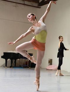 a young ballerina is practicing her moves in the dance studio with other dancers behind her