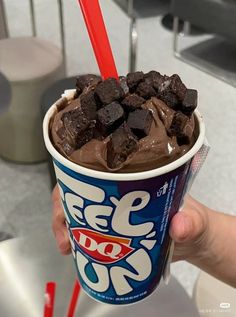 a person holding up a cup with ice cream and chocolate