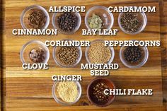 a wooden table topped with bowls filled with different types of spices and seasonings on top of each other